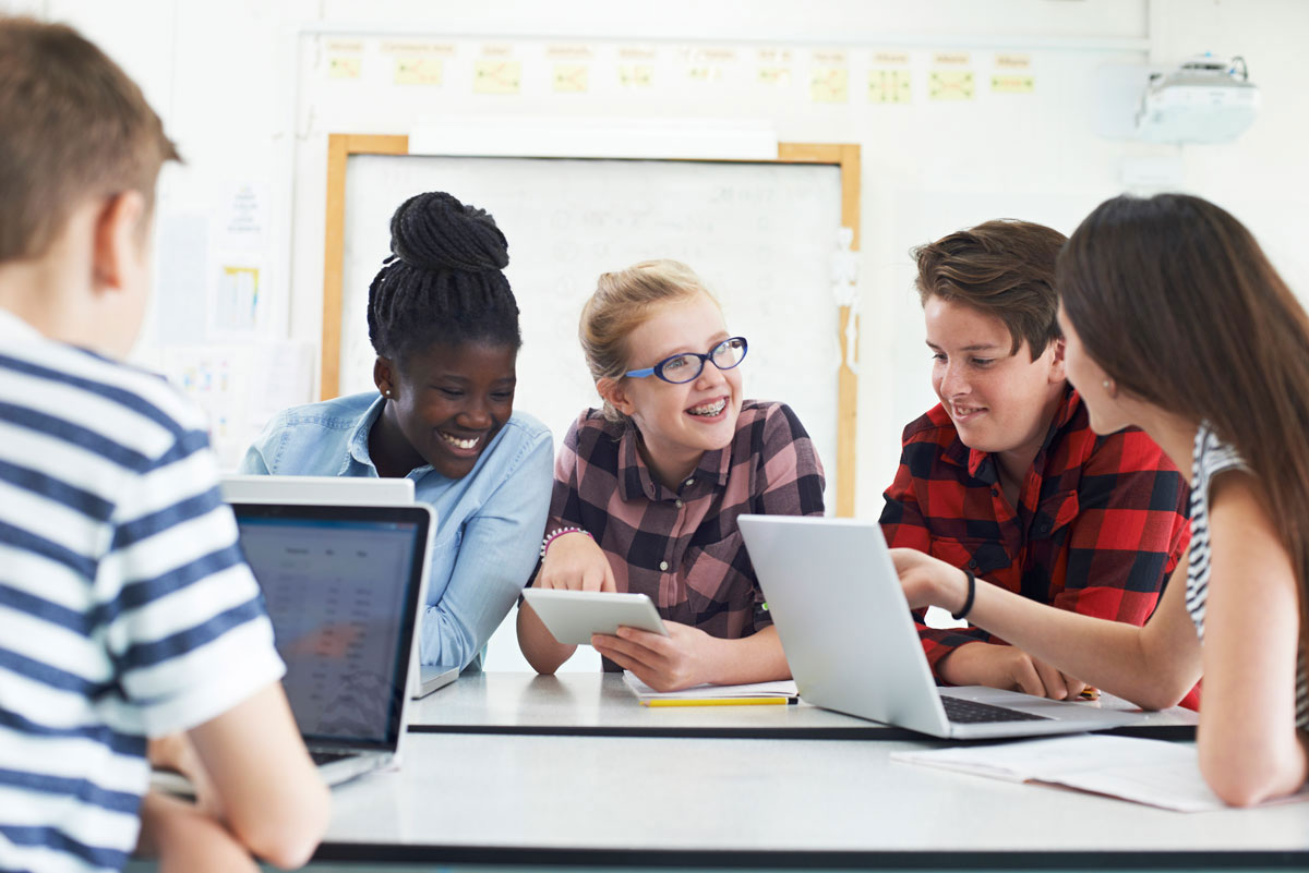 Stock image of a small group of young people using laptops in school